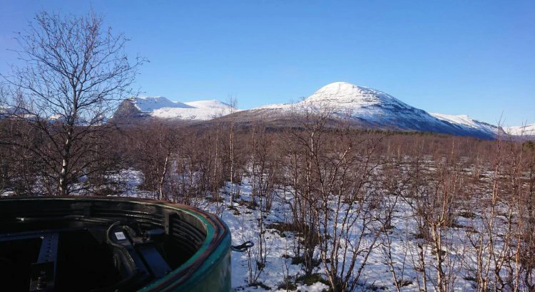 Mätstationen i Nikkaluokta med borttagen kupol i förgrunden, med snötäckta Kebnekaisefjällen i bakgunden